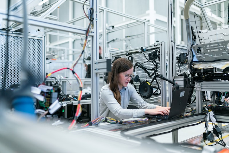 A person working at a laptop among automation equipment and cabling in an engineering facility — suggested image — client to supply the final photograph